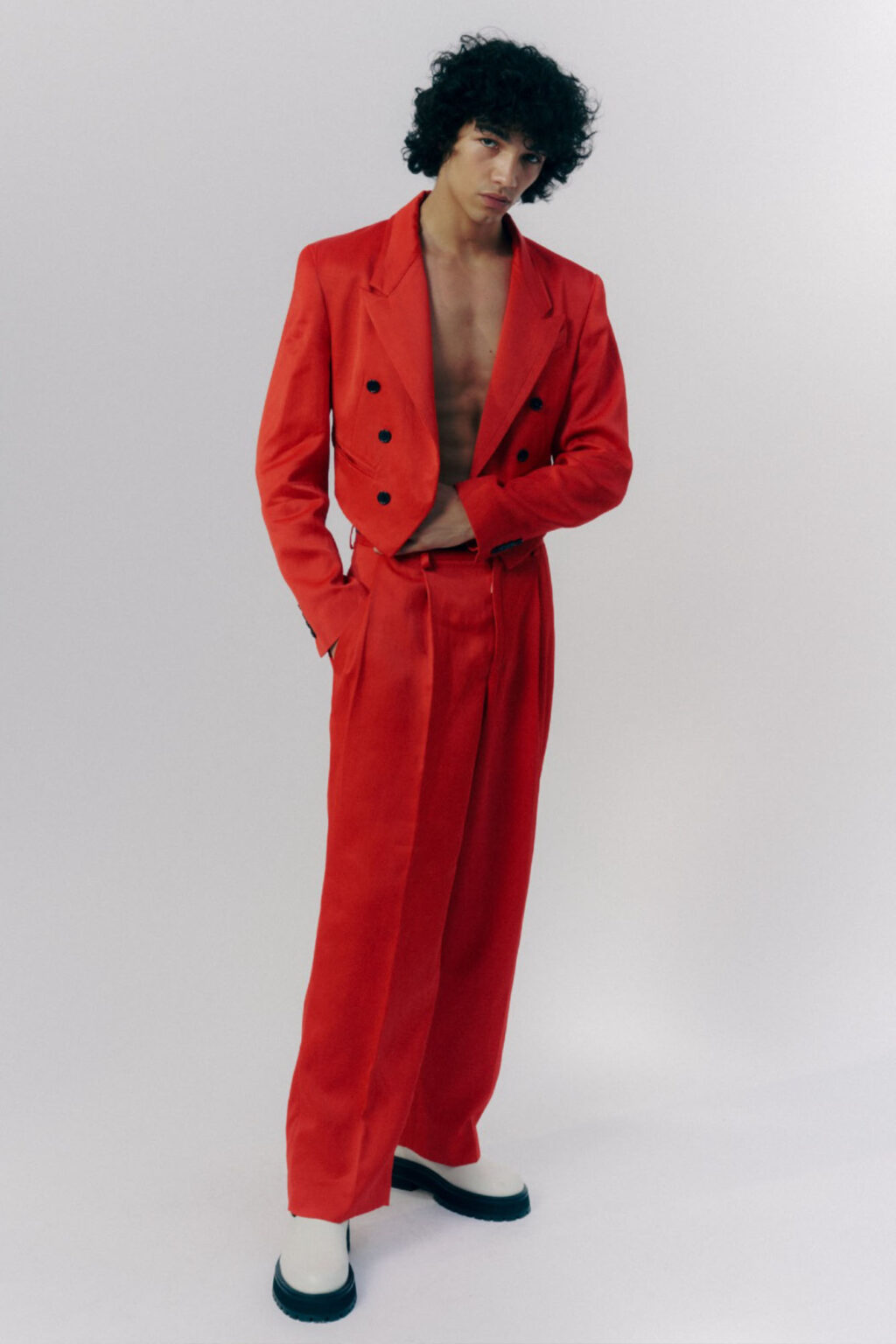 Model in a deep red suit, posing in a white studio, Scheiderei Hamburg, atelier dreisieben
