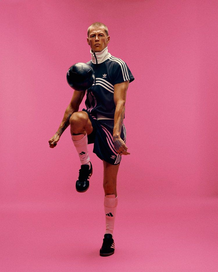 Model dressed in a Adidas x huni outfit dribbling a ball in front of a pink wall, fashion, atelier dreisieben Hamburg schneiderei, maßanfertigung
